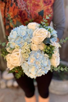 a woman holding a bouquet of white and blue flowers