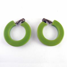 These cherry green Bakelite hoop earrings have patinated gold tone clip backs. They hold securely without pinching. Each earring is 1 7/16" across and 3/16" wide. The green material tests positively as Bakelite. Condition is very fine. Please use the "View Shop Policies" link on the lower right of each item page for important information before you order. Retro Clip-on Hoop Earrings, Retro Green Clip-on Earrings, Green Enamel Clip-on Earrings, Vintage Green Clip-on Jewelry, Luxury Vintage Green Clip-on Earrings, Antique Green Clip-on Jewelry, Green Enamel Vintage Earrings, Bakelite Jewelry, Vintage Bakelite