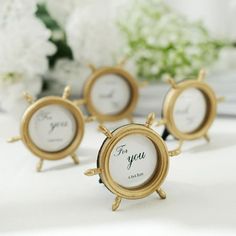 four small gold frames sitting on top of a table next to white flowers and greenery