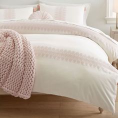 a white bed with pink comforter and pillows