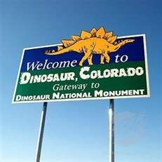 a welcome sign for the dinosaur, colorado national monument in front of a blue sky