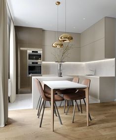 a dining room table and chairs in front of a kitchen with gold lights hanging from the ceiling