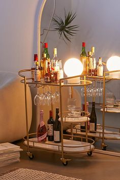 a bar cart with wine glasses and bottles on it