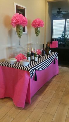 the table is decorated with pink flowers and wine bottles