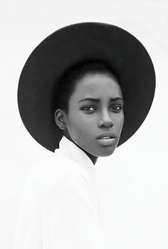 a black and white photo of a woman wearing a hat