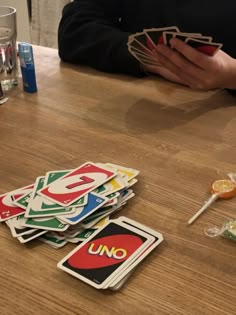 a person sitting at a table with some cards on top of it and drinks in front of them