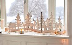 a window sill with christmas decorations and candles on it, in front of a snowy scene