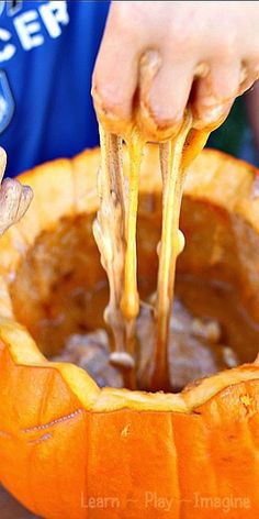 a person dipping some food into a pumpkin