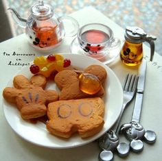 a white plate topped with cut out cookies next to utensils and a tea pot