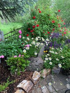 a garden filled with lots of flowers next to a fence