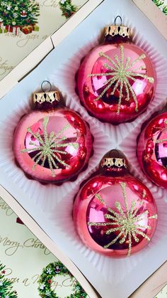 four pink christmas ornaments sitting on top of a white plate next to green and red decorations