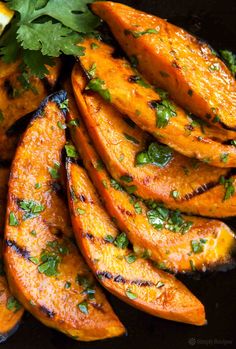 grilled sweet potato wedges with cilantro and parsley on a black plate