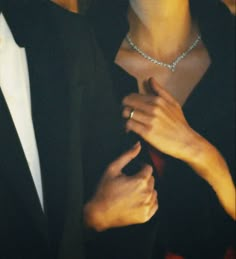 a man and woman are dressed up in formal attire, one is adjusting the tie