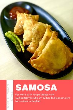 samosa on a black plate with asparagus and ketchup