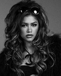 a woman with long hair wearing sunglasses and a fur coat is posing for a black and white photo