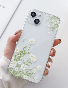 a woman is holding her phone case with daisies on it