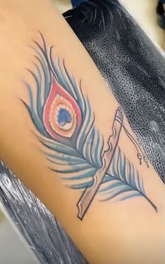 a woman's leg with a feather and an arrow tattoo on it