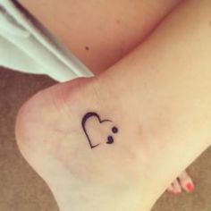 a woman's foot with a small heart tattoo on her left ankle and the word love written in black ink