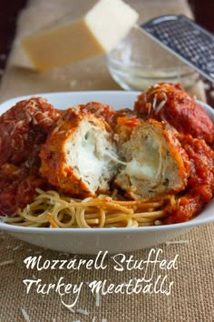 a white bowl filled with spaghetti and meatballs on top of a cloth covered table