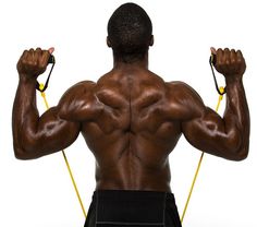 the back of a man with no shirt on, holding two yellow ropes in his hands