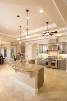 a large kitchen with an island in the middle and two ceiling fans hanging from the ceiling