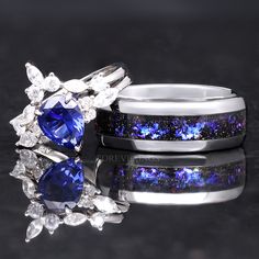 two wedding rings with blue and white stones on them, one is surrounded by diamonds