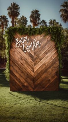 a wooden wall with the words better together written on it and greenery around it