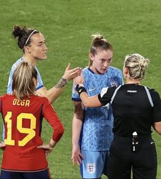 three female soccer players are talking to each other