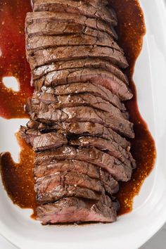 sliced steak on a white plate with sauce