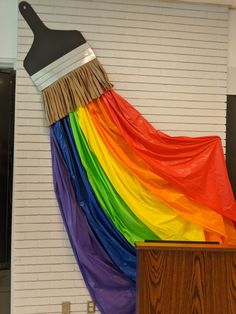 there is a large rainbow colored brush on top of a podium in front of a white brick wall