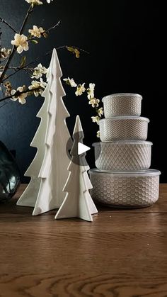 three white christmas trees sitting on top of a wooden table