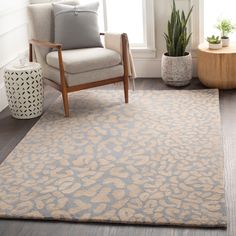 a living room area with a chair, rug and potted plant in the corner