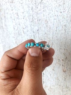 a person is holding some kind of ring in their left hand, with turquoise stones on it