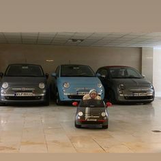 three small cars parked next to each other in a parking garage with two men driving them