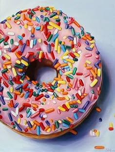 a donut with pink frosting and sprinkles on a white surface