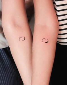 two people with matching tattoos on their arms, one is holding the other's arm