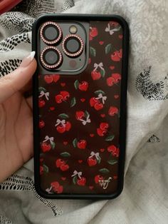 a person holding an iphone case with red roses on it and two buttons attached to the back