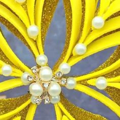 a close up view of a yellow flower with pearls on it