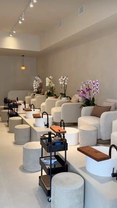 a room filled with lots of white couches next to tables and flowers in vases