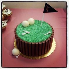 a golf themed cake on a pink tablecloth with cupcakes in the background