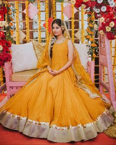 a woman sitting on top of a wooden bench in a yellow dress and headpiece