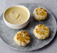 four peeled oranges on a plate next to a bowl of dip