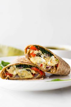 two burritos on a white plate with green leaves