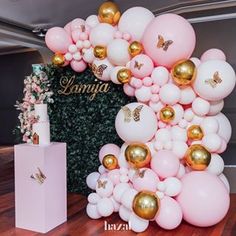 the balloon arch is decorated with gold, white and pink balloons