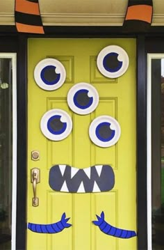 a yellow door decorated with paper plates and fake eyes