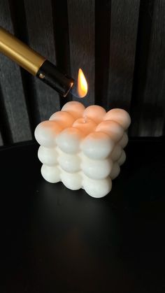 a lit candle sitting on top of a black table next to a golden object with a lighter sticking out of it