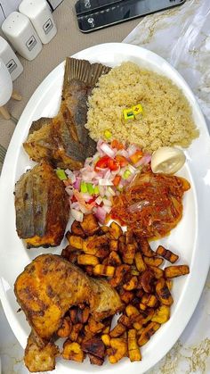 a white plate topped with meat, rice and veggies next to utensils