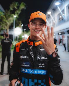 a man in an orange hat making the vulcan sign with his hand while standing next to other people