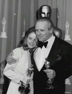 an old black and white photo of two people holding oscars