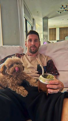 a man sitting on a couch with a dog and bowl of food in his hand